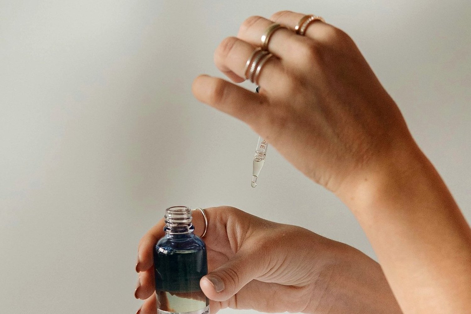 Hands holding skincare product for Dewy sunscreen without looking greasy.