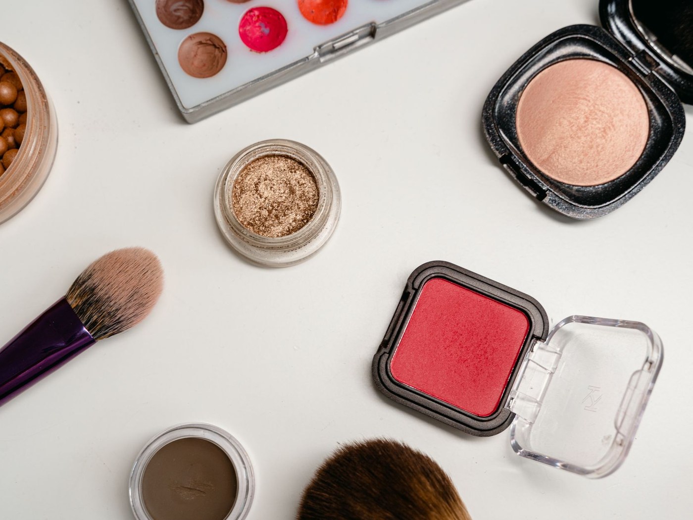 Powder brush and compact makeup products arranged on a clean vanity