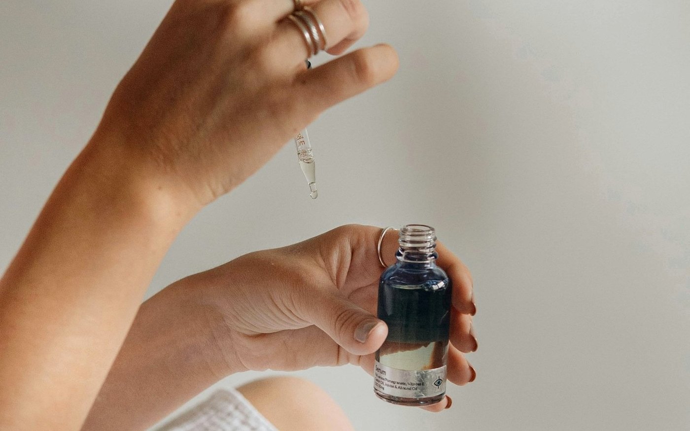 Hand holding a small skincare bottle for sunscreen reapplication over makeup