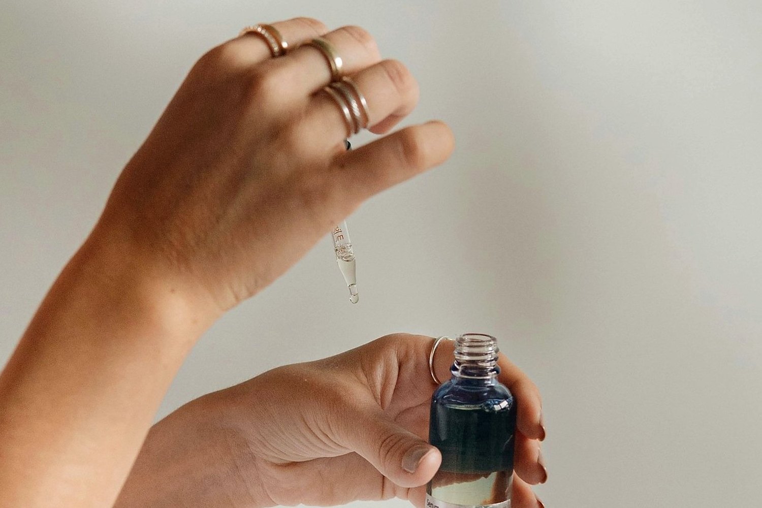 Hands holding skincare product for Reapplying sunscreen over makeup without wrecking the base.