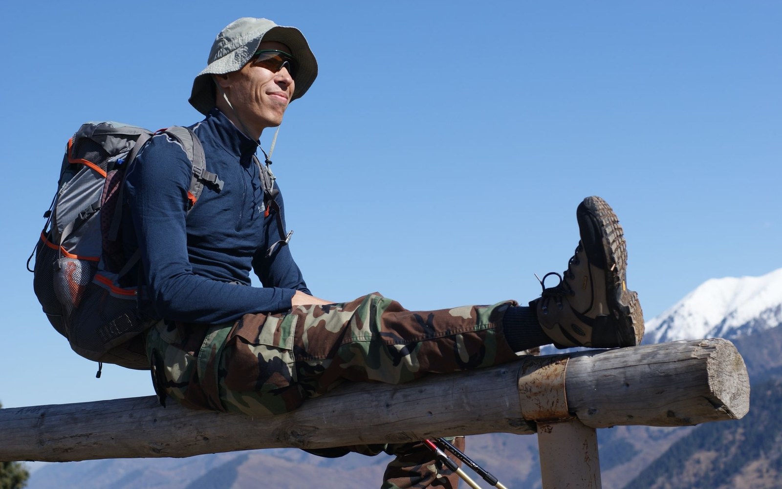 Hiker wearing layered sun-protective clothing, hat and backpack outdoors