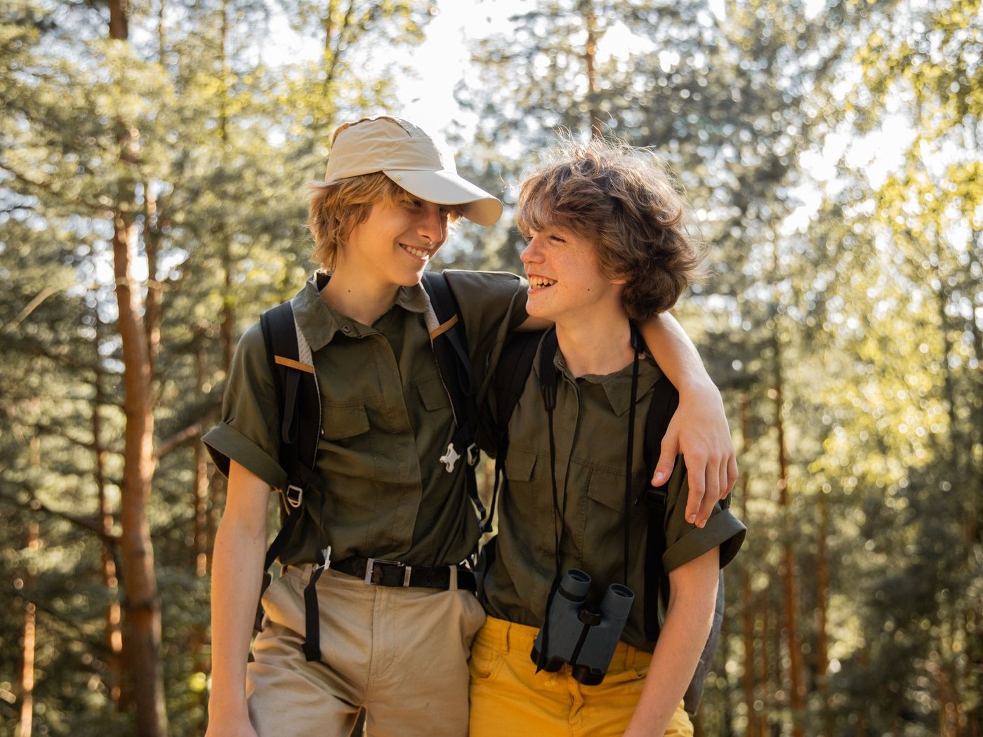 Two hikers wearing lightweight shirts and hats on a wooded trail