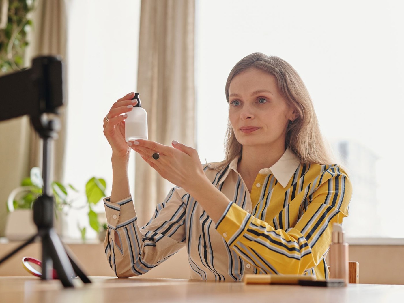 Person filming a skincare application demonstration with a phone and camera setup