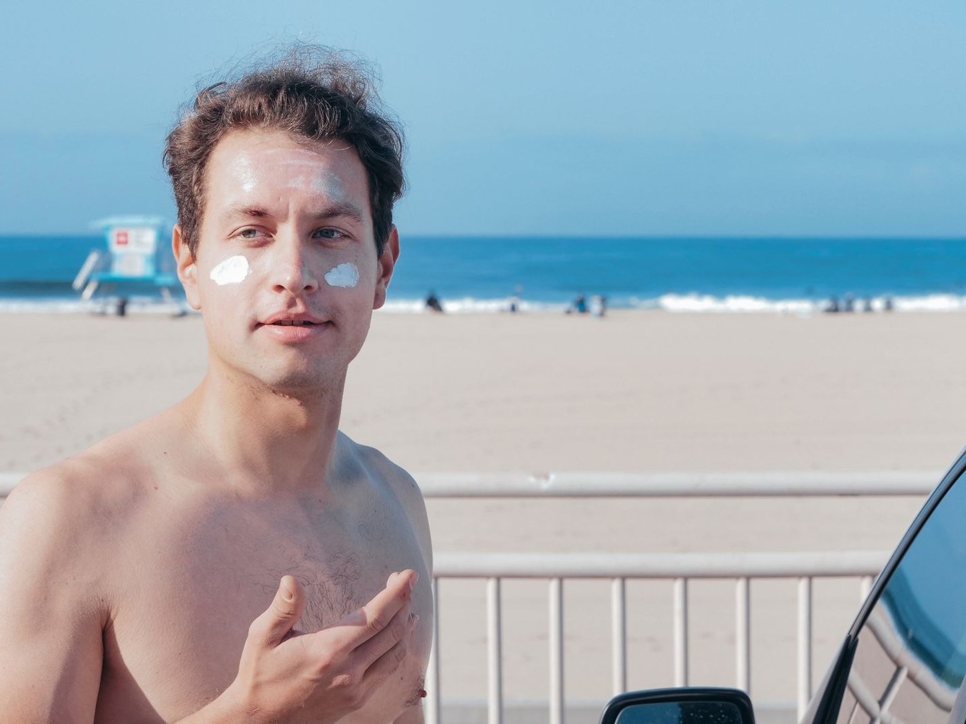 Person applying visible sunscreen patches across the face before checking coverage